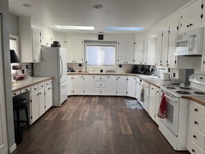 A modern kitchen with white cabinets, a built-in oven, and a skylight.