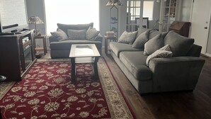 A living room with a sofa, a coffee table, a TV on a cabinet, a patterned rug, and a lamp. - Century Farm in Horse Heaven Hills, Tri-Cities WA (Kennewick)