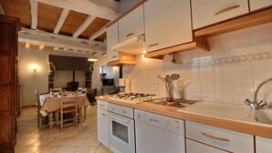 A kitchen with wooden beams, white cabinets, a stove, and a sink. - Gîte 4 persons Plestin-les-Grèves (Plestin-les-Grèves)