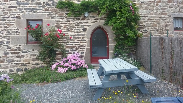 A stone building with a red door, windows, and a wooden fence. - Gîte 4 persons Plestin-les-Grèves (Plestin-les-Grèves)