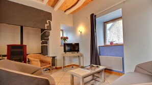 A living room with a fireplace, a television, a table, and two sofas. - Gîte 4 persons Plestin-les-Grèves (Plestin-les-Grèves)