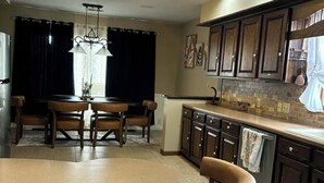 A modern kitchen with dark wooden cabinets, a round dining table, and a chandelier. -  3-bed 2.5 bath, outdoor pool May 31-Sep 30th/AC/in Bellevue (Bellevue)
