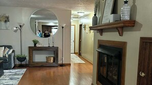 A spacious living room with hardwood flooring, a fireplace, a curved bench, a round mirror, and a wooden shelf with decorative items. -  3-bed 2.5 bath, outdoor pool May 31-Sep 30th/AC/in Bellevue (Bellevue)