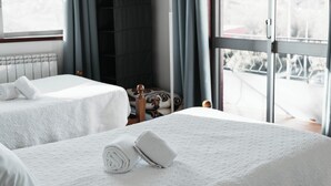 A hotel room with two beds, a TV, a window with curtains, and a view of the outside. - Itinerant Nightfall - Twin suite with balcony by Lethes Legacy (Ponte de Lima)