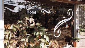 A hotel entrance with a sign reading 'Residencial Hotel,' decorative glass patterns, and potted plants. - Itinerant Nightfall - Twin suite with balcony by Lethes Legacy (Ponte de Lima)