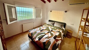 Ein Schlafzimmer mit Bett, einem Fenster mit Blick, einem Heizkörper und einer Holzleiter.