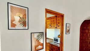 Ein Flur mit gerahmten Kunstwerken, einer Holztür und einem Küchenbereich mit Schränken.
