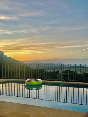 Ein Pool mit Blick auf einen Sonnenuntergang und ferne Berge.