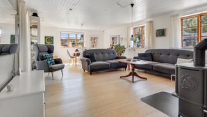 A modern living room with a sofa, armchairs, a dining table, and a kitchen area with a stove. - "Fausta" - 2km from the sea by Interhome (Gedser)