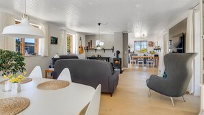 A modern interior with a dining area, grey sofas, a fireplace, and a kitchen in the background. - "Fausta" - 2km from the sea by Interhome (Gedser)