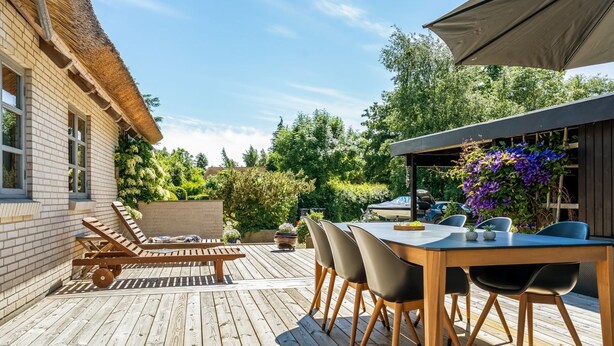 A wooden deck with a table and chairs, a lounge chair, and a covered area with plants. - "Fausta" - 2km from the sea by Interhome (Gedser)