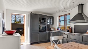 A modern kitchen with grey cabinets, a wooden dining table, and a red bowl on the counter. - "Fausta" - 2km from the sea by Interhome (Gedser)