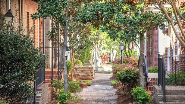Un vialetto in mattoni, costeggiato da alberi e da un edificio in laterizio.