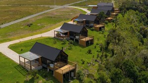 Een rij houten vakantiehuisjes met een helder uitzicht op het omliggende landschap en een weg in de verte.