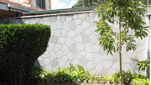 A stone wall with a geometric pattern, a small tree, and a well-maintained hedge. - LA FONT HOUSE Near JKIA Nairobi (Nairobi)