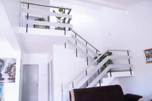 Una escalera moderna con barandas blancas y plantas en macetas, que conduce a un piso superior.