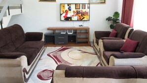 A living room with a sofa set, a flat-screen TV, a staircase, and a plant. - LA FONT HOUSE Near JKIA Nairobi (Nairobi)