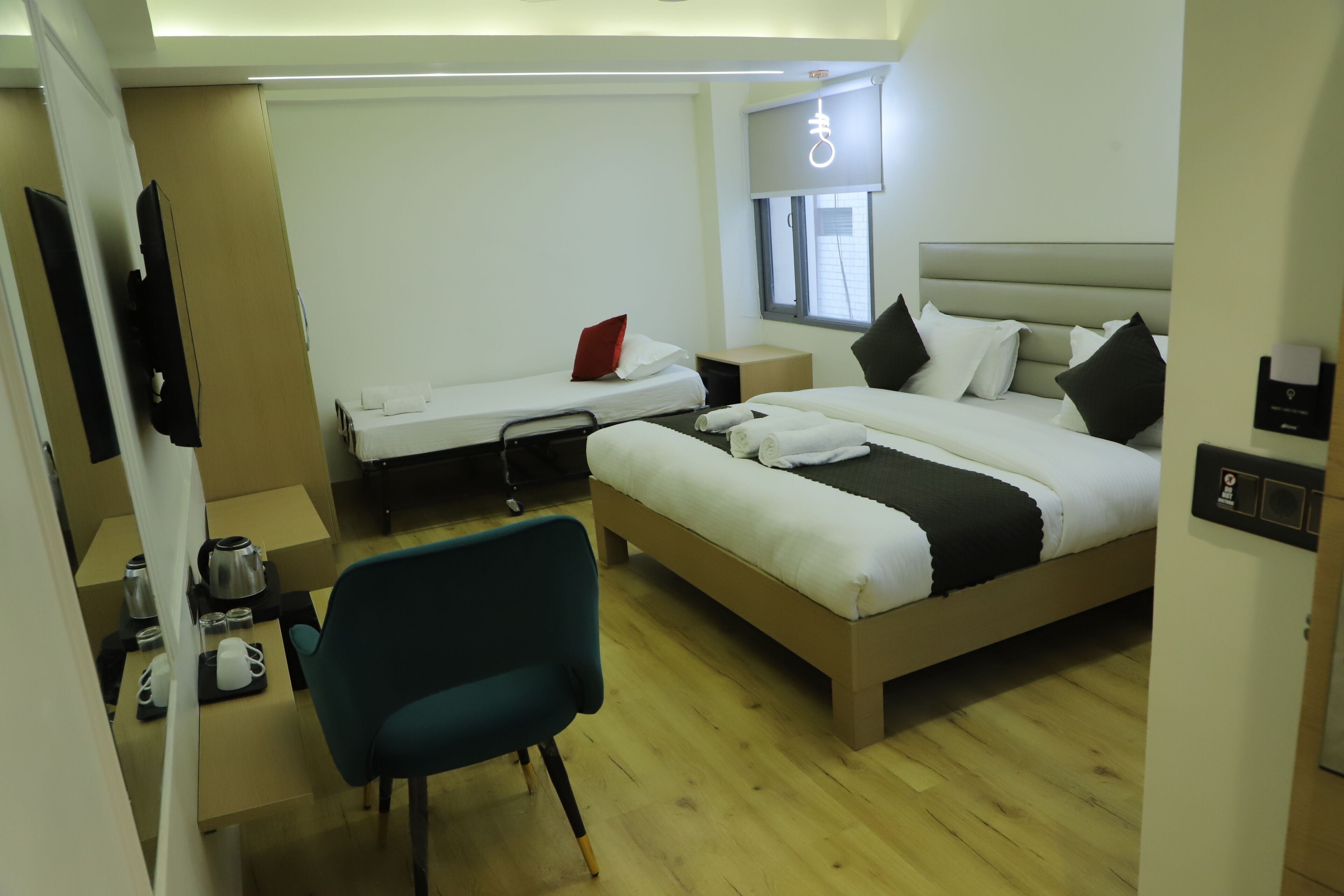 Una habitación de hotel con cama, escritorio, silla, televisor y ventana.