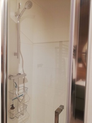 A shower with a handheld showerhead, a wall-mounted towel rack, and a metal towel rack.