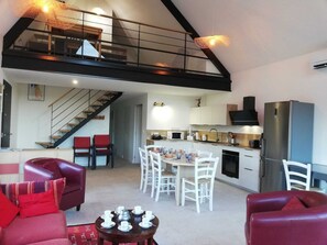 Un intérieur moderne comprenant un espace repas, une cuisine et un escalier menant à un niveau supérieur.