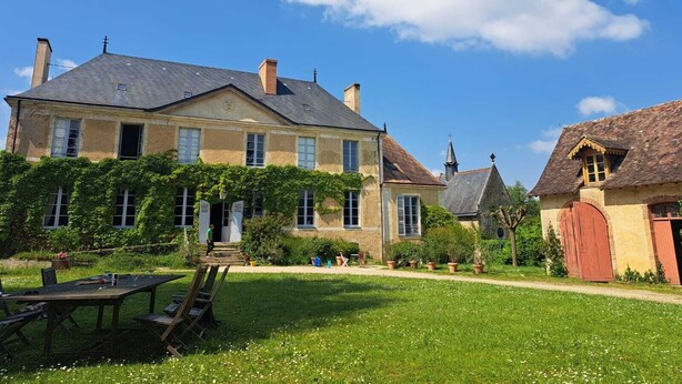 Ein großes Steinhaus mit Garten und Sitzgelegenheiten im Freien.