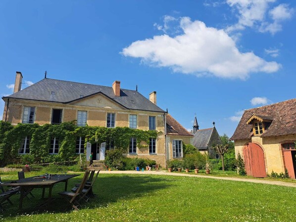 Ein großes Steinhaus mit Garten und Sitzgelegenheiten im Freien.