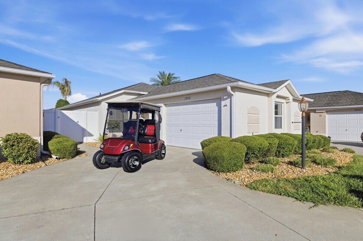 A residential garage with a red golf cart parked in front.