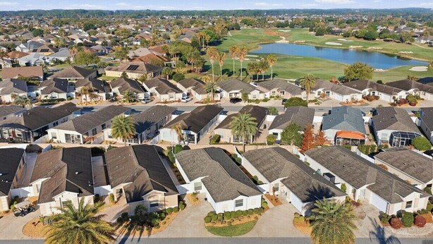 Un barrio residencial con casas, un campo de golf y un lago.