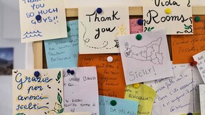 A bulletin board with various handwritten notes and messages pinned to it. - Room 8 A (Trapani)