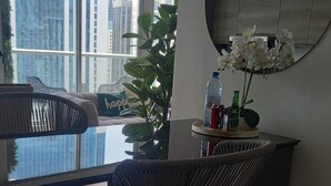 A modern room with a glass table, wicker chairs, a potted plant, and a water bottle. - Modern Skyline Apartment in Marbella | Pool, Gym, and a Short Walk to the Cinta Costera (Panamá)