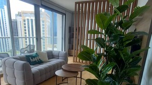 A living room with a sofa, coffee table, and potted plant. - Modern Skyline Apartment in Marbella | Pool, Gym, and a Short Walk to the Cinta Costera (Panamá)