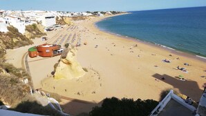 Una spiaggia costiera con una scogliera rocciosa, un edificio con insegna e vista libera sul mare.