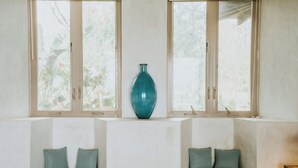 A room with two seating areas, a large vase, and windows with a view of greenery. - Beachfront Luxury Villa in Playa Venao (Los Santos Province)
