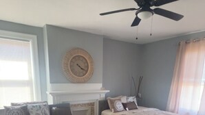 A bedroom with two beds, a ceiling fan, a fireplace, and a clock on the wall. - Delightful and Remodeled 5-bedroom house near the North Shore and Draft Event (Pittsburgh)