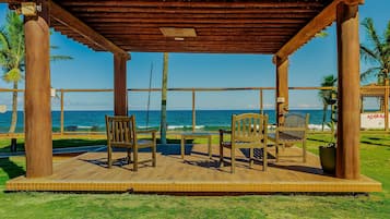 A wooden deck with chairs and a table, overlooking the ocean.