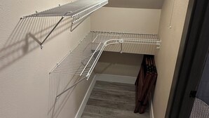 A room with a built-in closet with metal shelving, a wooden floor, and a light fixture on the ceiling. - Private Ptarmigan Suite (Hayden)