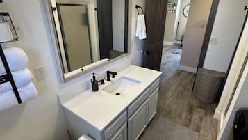 Une salle de bain avec un double lavabo, des toilettes, un grand miroir et un espace douche.