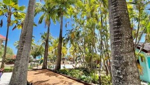 Ein tropisches Resort mit Palmen, einem Sandstrand und einem Pool.