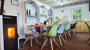 Interior de restaurante con suelo de ladrillo, mesas de madera y sillas de colores.