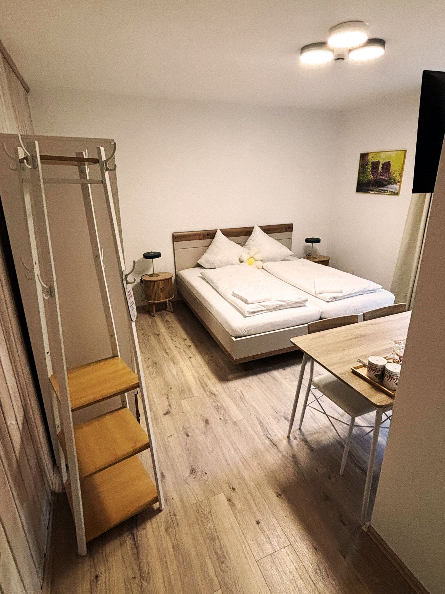 Une chambre à coucher avec un lit, des tables de chevet, un bureau, une chaise, une échelle et un tableau accroché au mur.