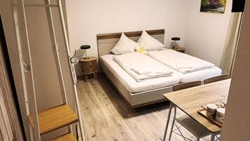Une chambre à coucher avec un lit, des tables de chevet, un bureau, une chaise, une échelle et un tableau accroché au mur.