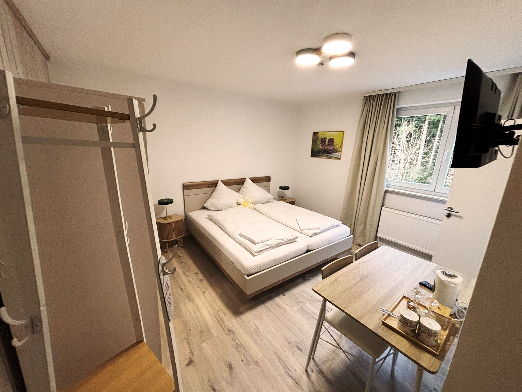 A bedroom with a bed, bedside tables, a desk, a chair, and a window.