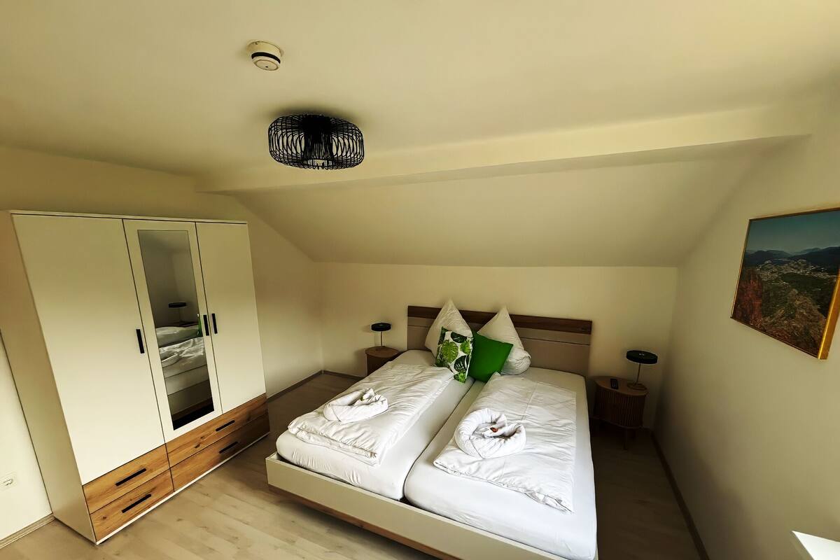 A bedroom with a bed, wardrobe, bedside tables, and a ceiling light fixture.