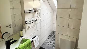 A small, modern bathroom with a shower, toilet, and sink.