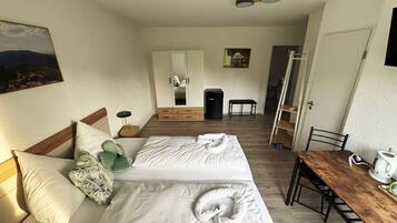 Ein Hotelzimmer mit Bett, Nachttisch, Stuhl und Blick auf den Flur.