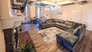 A living room with a sectional sofa, a fireplace, a dining area, and a staircase.