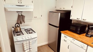 A compact kitchen with a gas stove, a refrigerator, a microwave, and a dishwasher. - Charming & Bright 1-bedroom w/private laundry & yard in Sacramento (Sacramento)