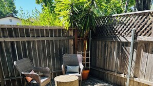 A patio area with wicker furniture, a round wicker table, and a potted plant. - Charming & Bright 1-bedroom w/private laundry & yard in Sacramento (Sacramento)