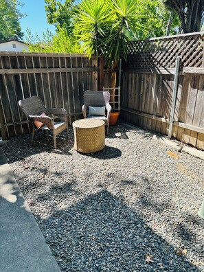 A patio area with wicker furniture, a round wicker table, and a potted plant.
