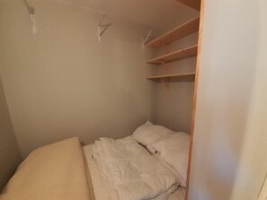 A small, single-bed room with a wooden headboard, a bed with white bedding, and a built-in shelf above the bed. - 20m from resort center, 5th floor, balcony, tv, ski locker, 21m², Valfréjus (Valfréjus)